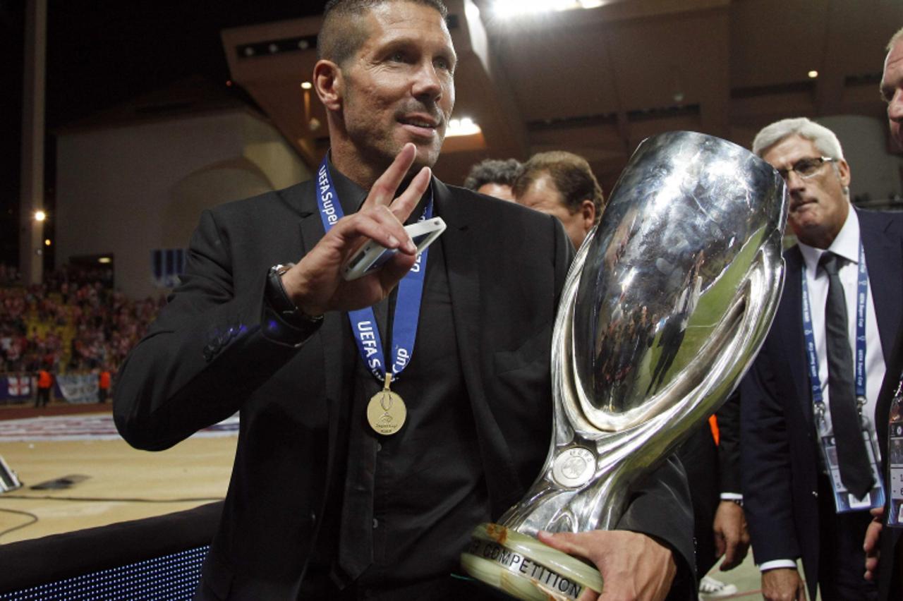 'Atletico Madrid\'s coach Diego Simeone holds the trophy as he celebrates their win against Chelsea in their Super Cup soccer match at Louis II stadium in Monaco, August 31, 2012. REUTERS/Eric Gaillar