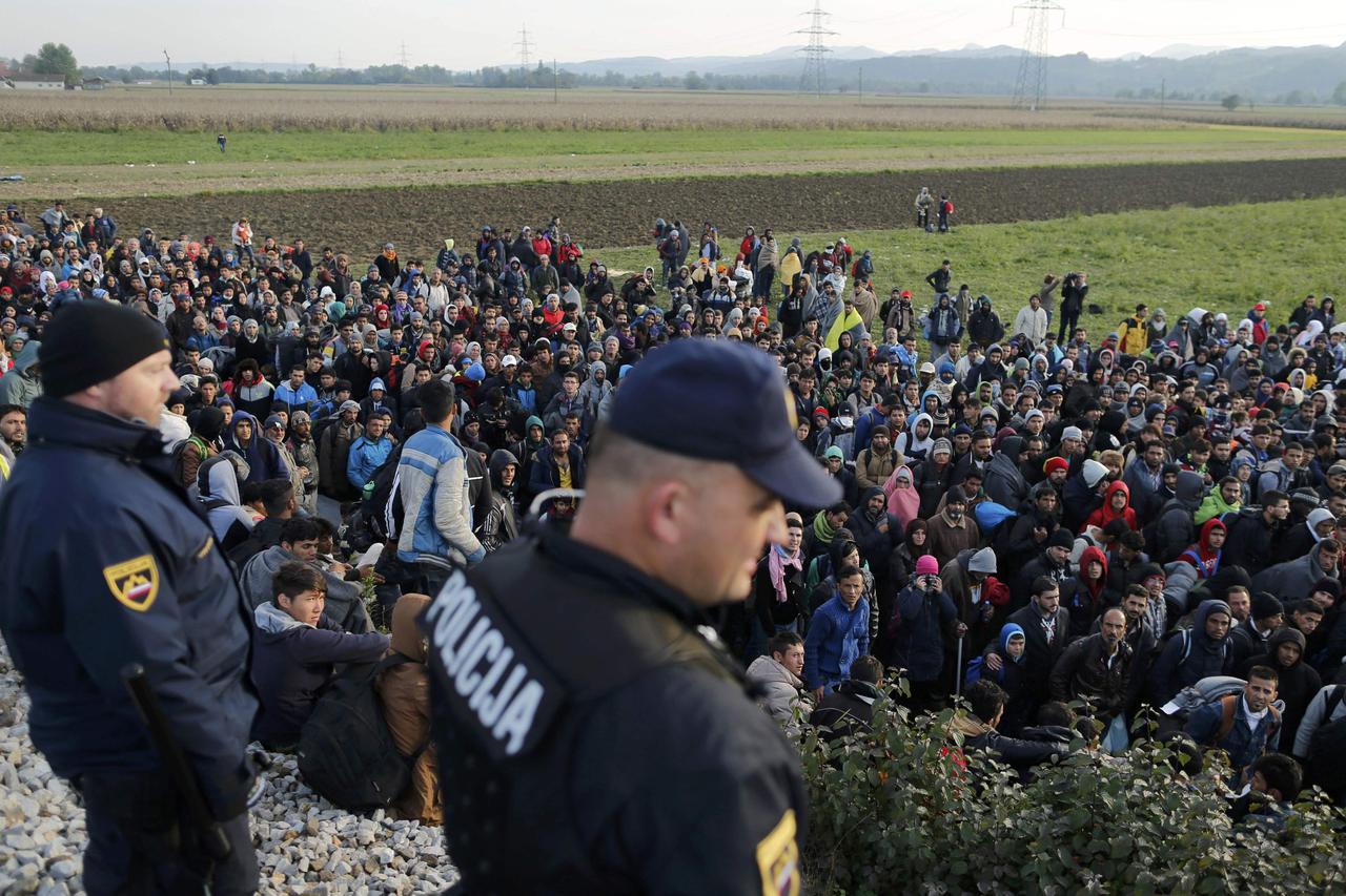 Slovenian police officers watch as migrants walk from Dobova towards a transit camp in Brezice, Slovenia October 21, 2015.   REUTERS/Antonio Bronic