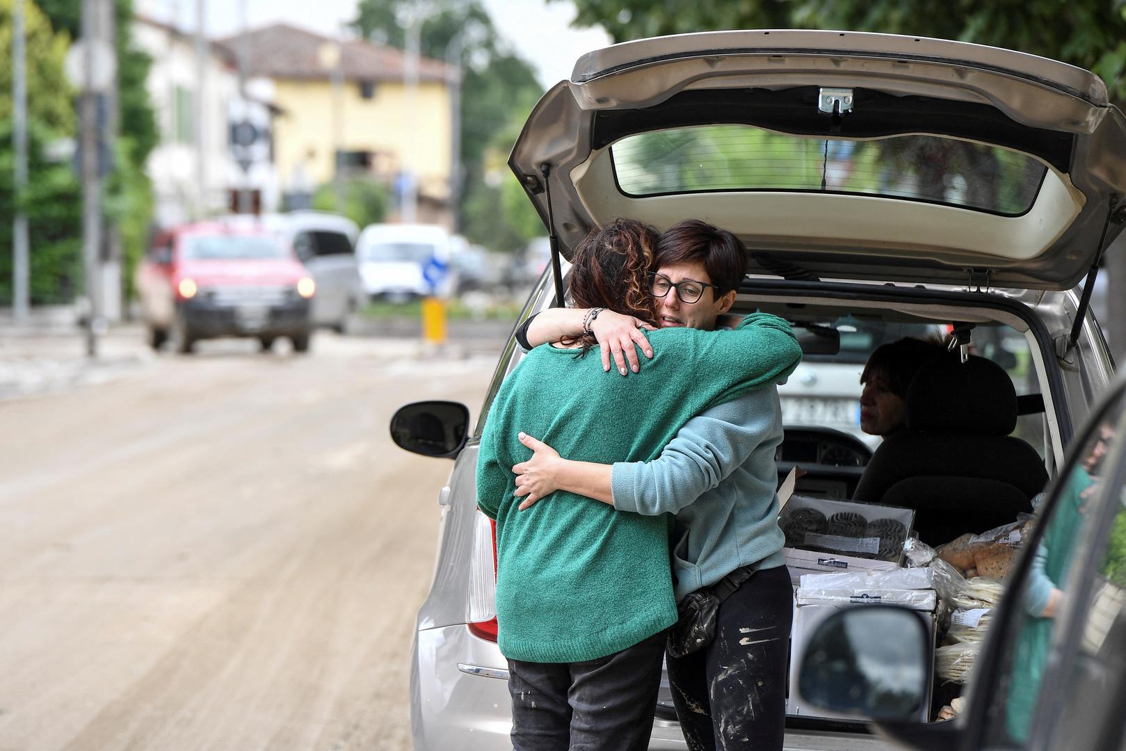 People embrace next to a car, after heavy rains hit Italy's Emilia Romagna region, in Castel Bolognese, Italy, May 18, 2023. REUTERS/Jennifer Lorenzini Photo: JENNIFER LORENZINI/REUTERS