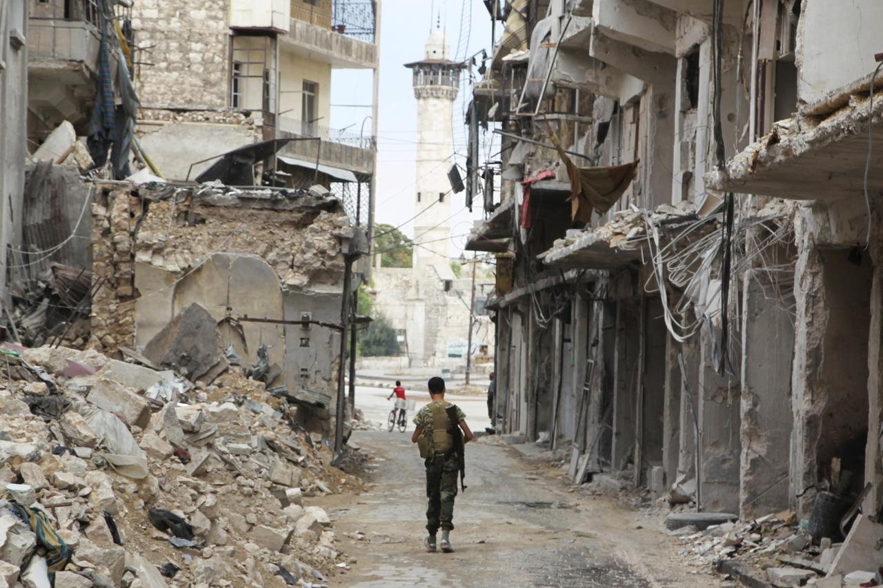 A Free Syrian Army fighter carries his weapon as he walks past damaged buildings in the old city of Aleppo, Syria, August 30, 2015. REUTERS/Abdalrhman Ismail