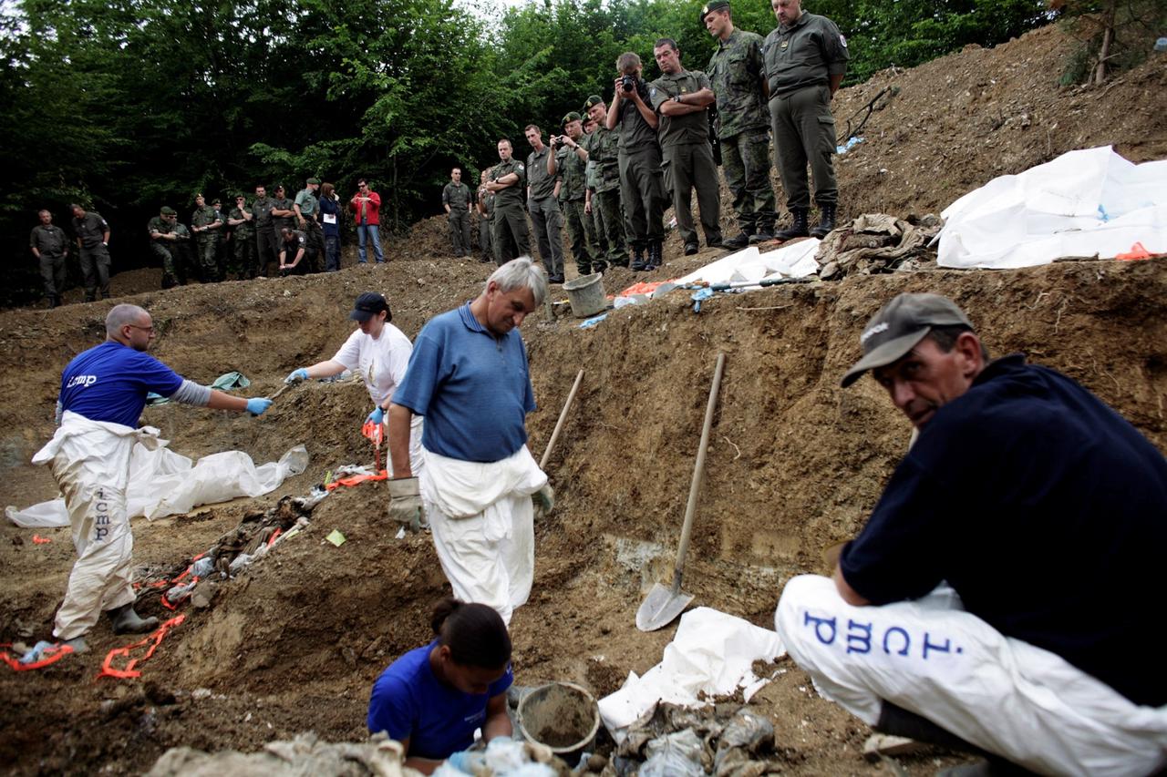 FILE PHOTO: EUFOR peacekeepers in Bosnia watch forensic experts from the ICMP work in a mass grave