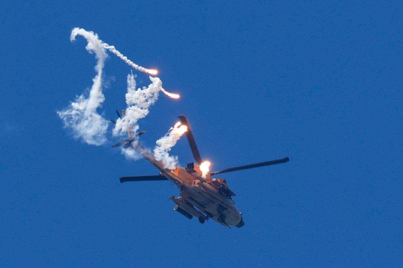 Israeli Apache helicopter releases flares as it flies over Lebanon as seen from Israel