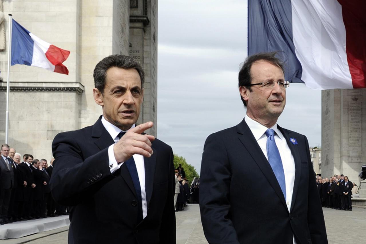 'Outgoing French President Nicolas Sarkozy (L) and newly-elected president Francois Hollande attend a ceremony at the Tomb of the Unknown Soldier at the Arc de Triomphe to mark the end of World War II
