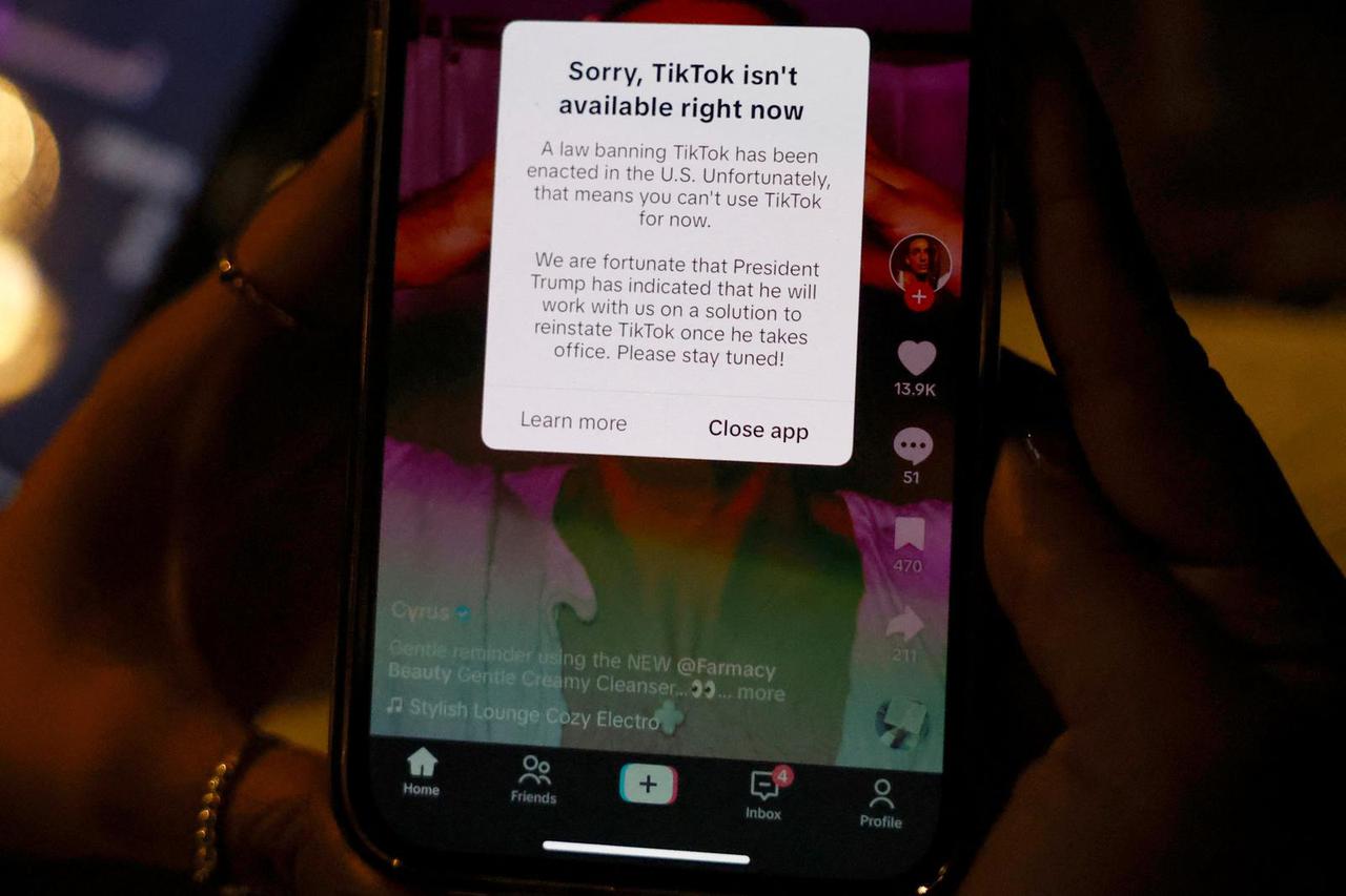 A woman poses with her smartphone displaying the TikTok app afterit stopped working in the United States late on Saturday