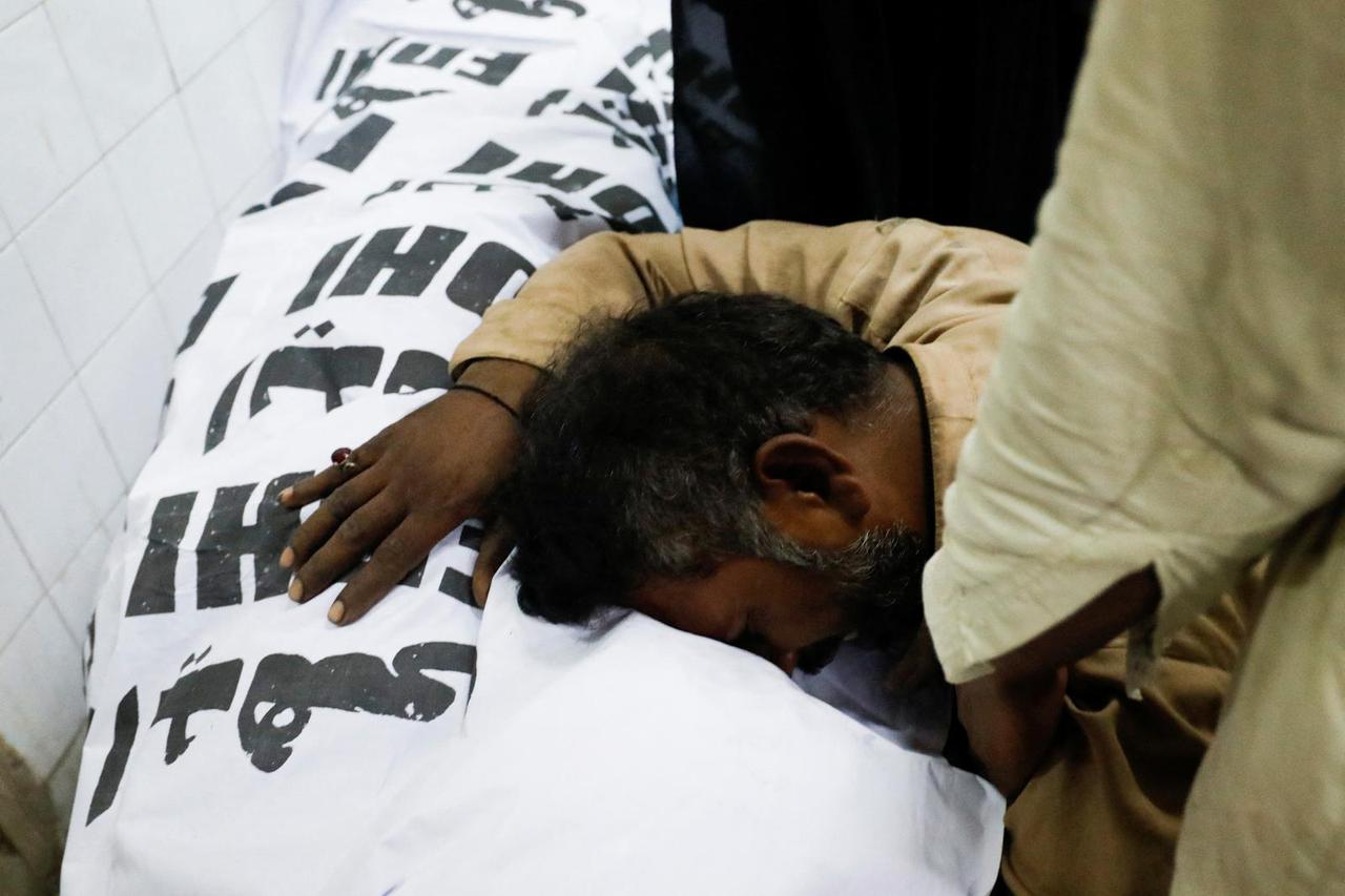 People mourn the death of a relative, who was killed along with others in a stampede during handout distribution, in Karachi