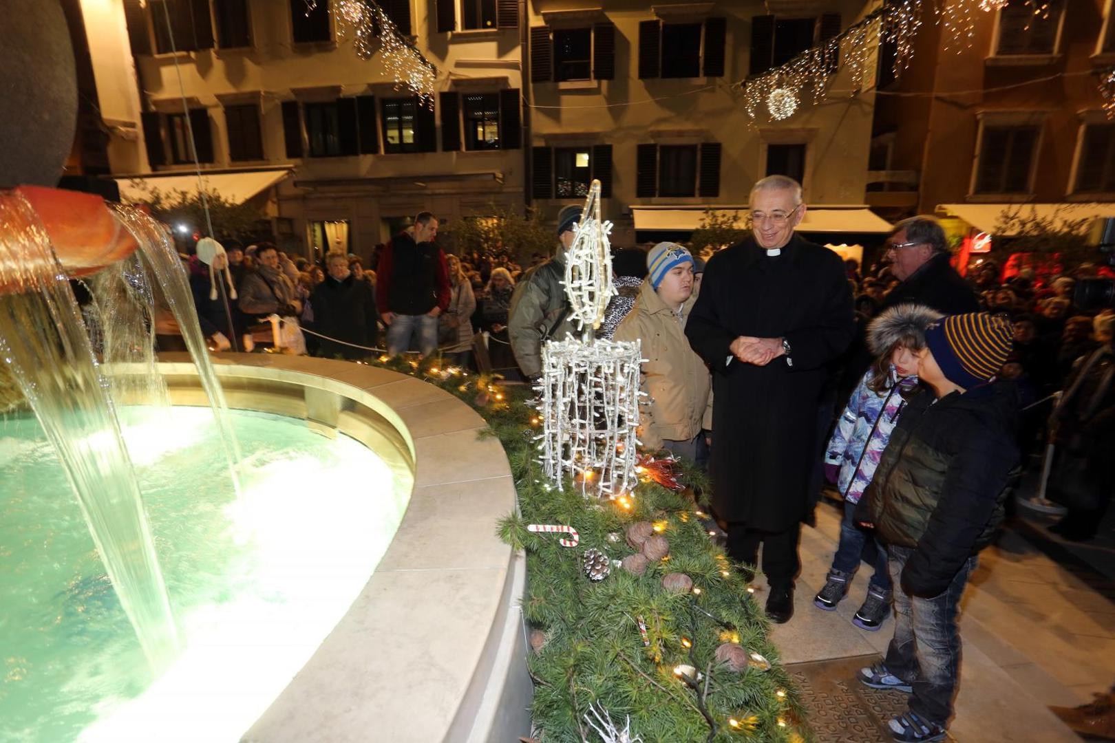 Prvu svijeću na adventskom vijencu postavljenom oko fontane na Koblerovom trgu upalio je riječki nadbiskup msgr Ivan Devčić u drustvu gradonačelnika Vojka Obersnela i učenika Centra za odgoj koji su ukrasili adventski vijenac.
