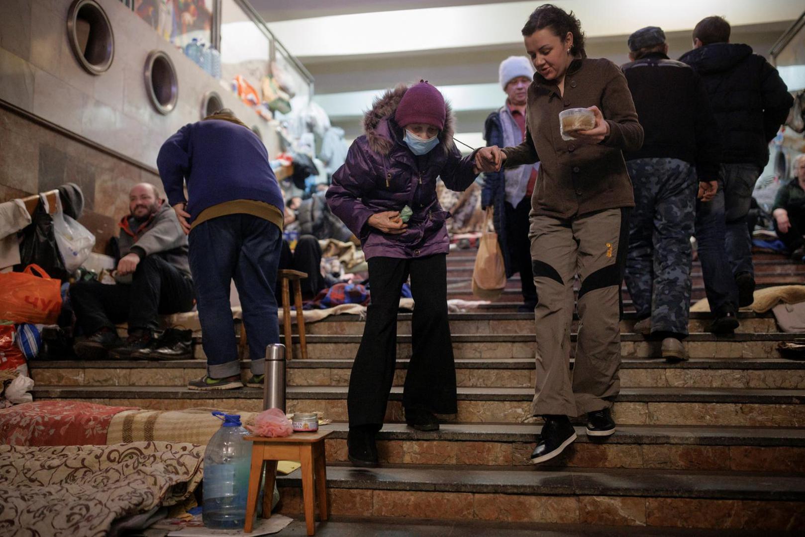 A woman helps an elderly person to walk down the stairs as they shelter in a metro station in northern Kharkiv from shelling in their neighbourhood as Russia's attack on Ukraine continues, Ukraine, March 24, 2022.  REUTERS/Thomas Peter Photo: Thomas Peter/REUTERS
