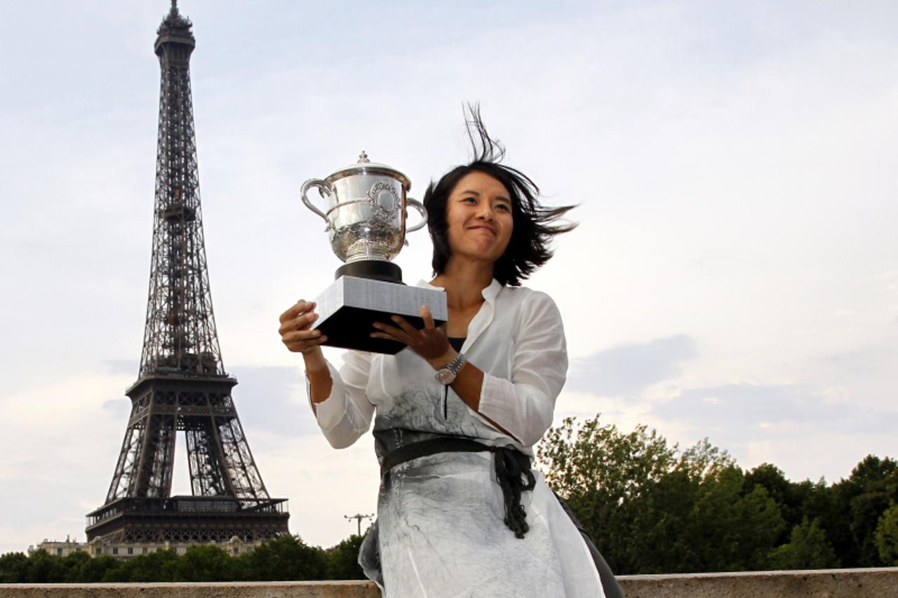 'China\'s Li Na holds the Roland Garros French Open tennis championship trophy in front of the Eiffel Tower on June 4, 2011 in Paris a few hours after winning the French Open Women\'s final. Li Na mad