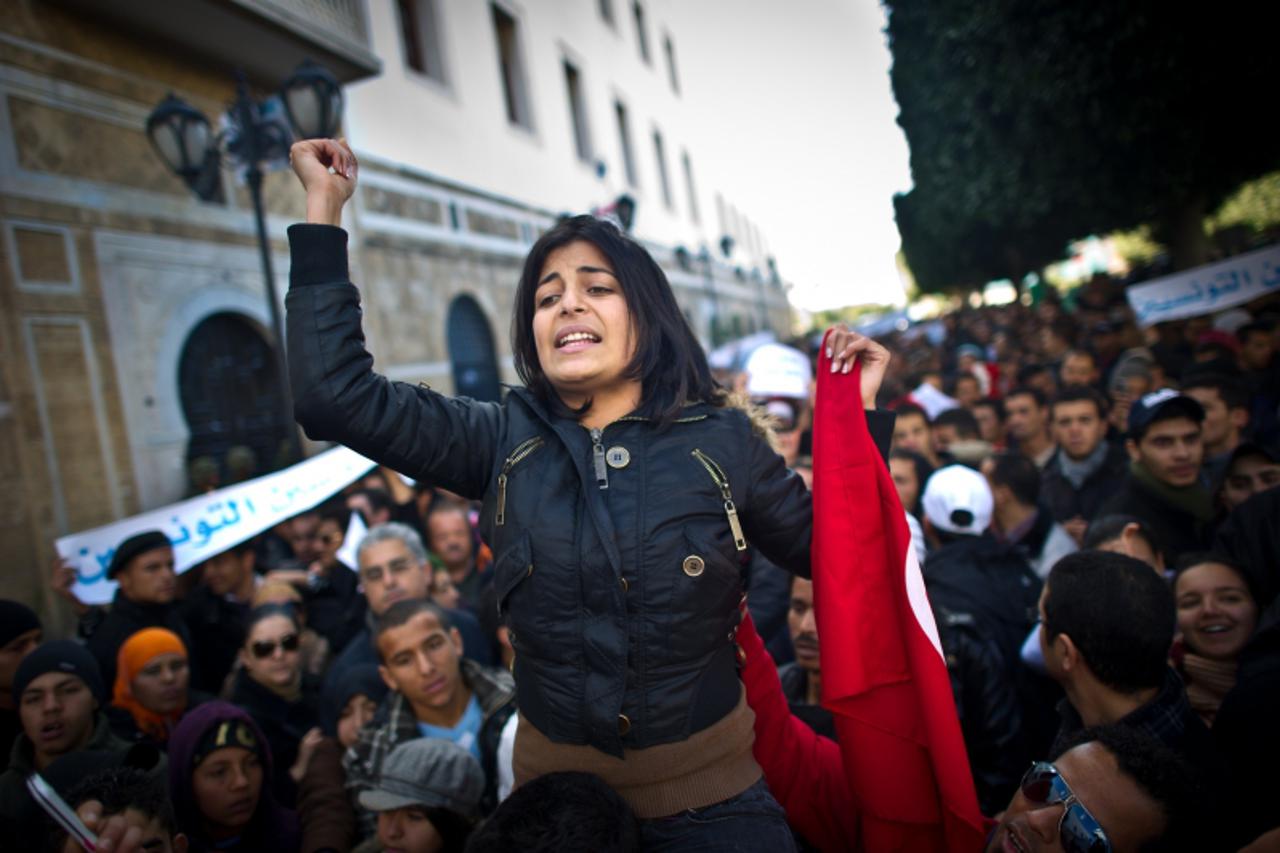 'A woman raises her fist during a demonstration calling on the new government to quit, on Bourguiba avenue in central Tunis on January 22, 2011. Thousands of people rallied in Tunisia today as the pri