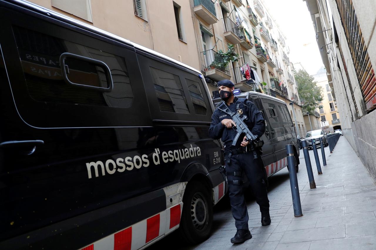 A police officer stands guard on the street as the intervention in a drug bust takes place in the El Raval neighbourhood of Barcelona