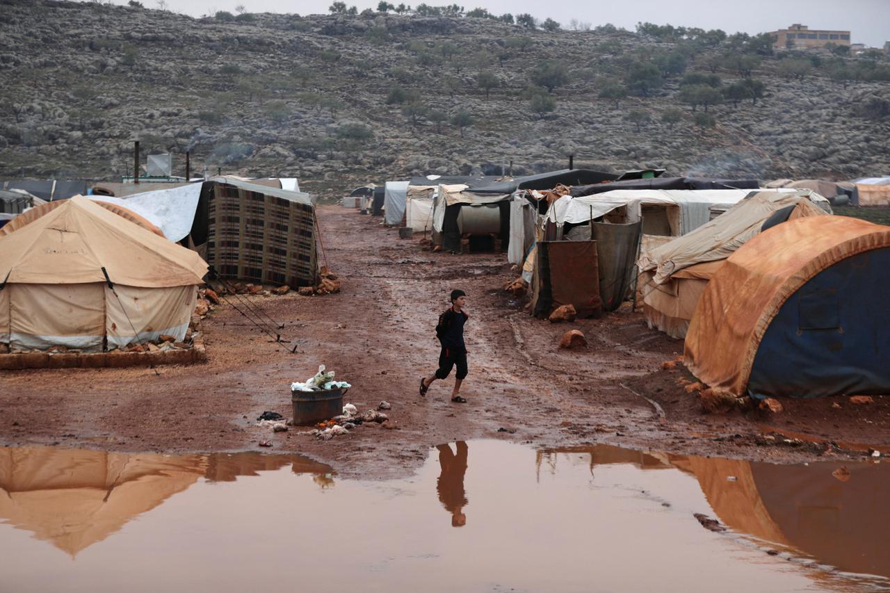 Internally displaced Syrian boy walks through mud after heavy rain at Kafr Arouk camp in Idlib