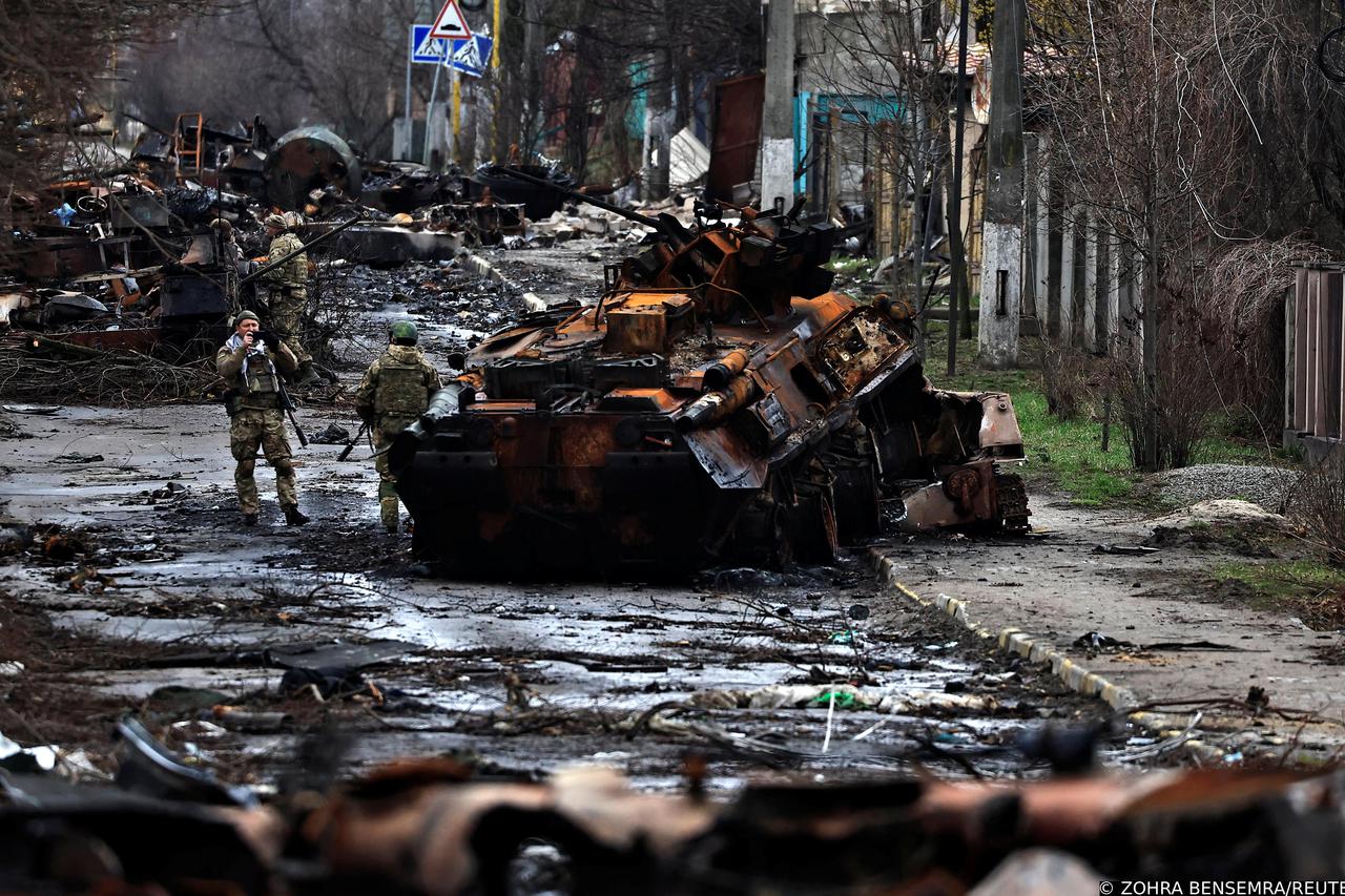 A soldier takes a photograph of his comrade as he poses beside a destroyed Russian tank and armoured vehicles, amid Russia's invasion on Ukraine in Bucha, in Kyiv region