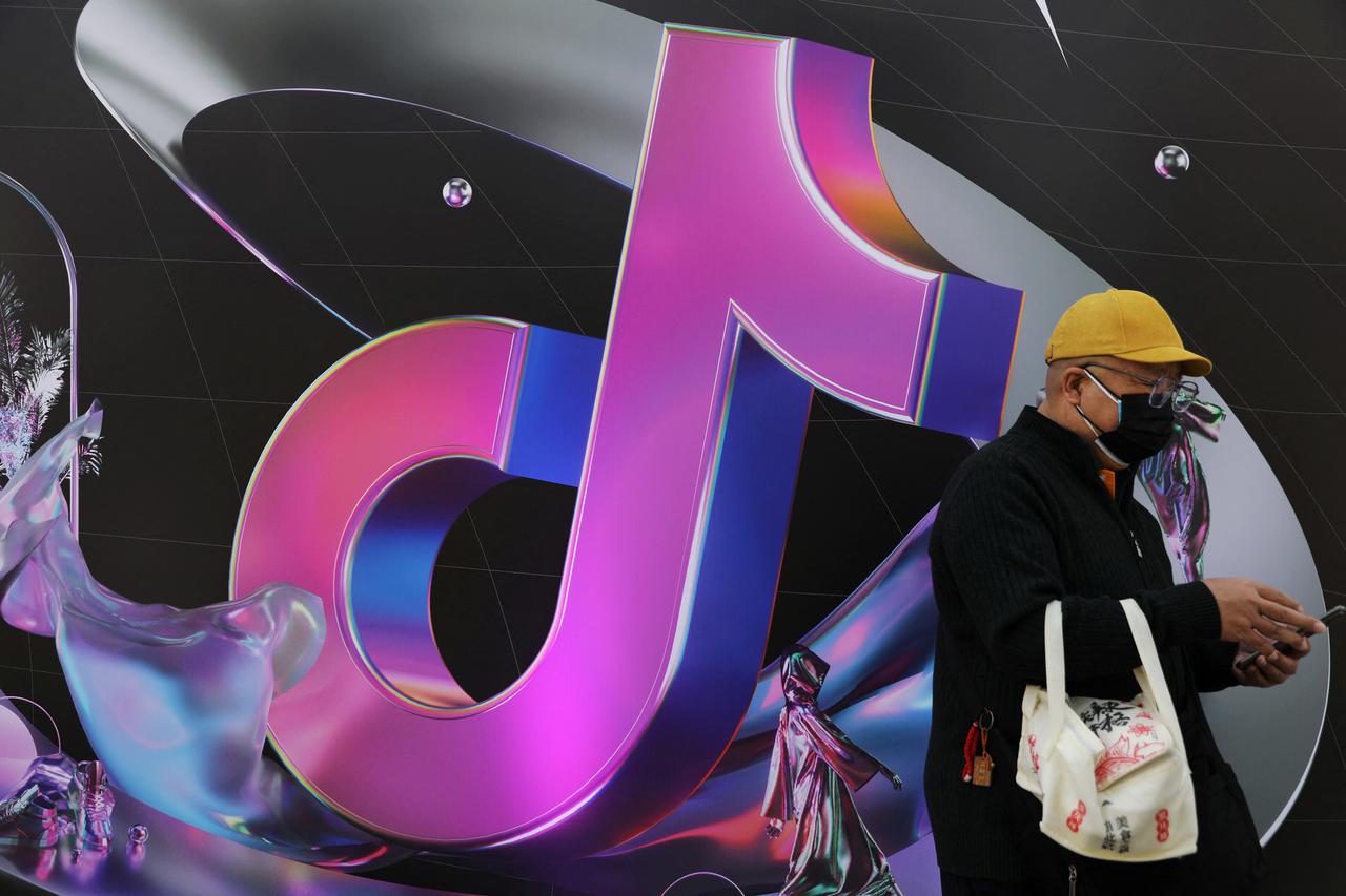 FILE PHOTO: Man stands near a giant sign of Chinese company ByteDance's app TikTok, known locally as Douyin, during China Fashion Week, in Beijing