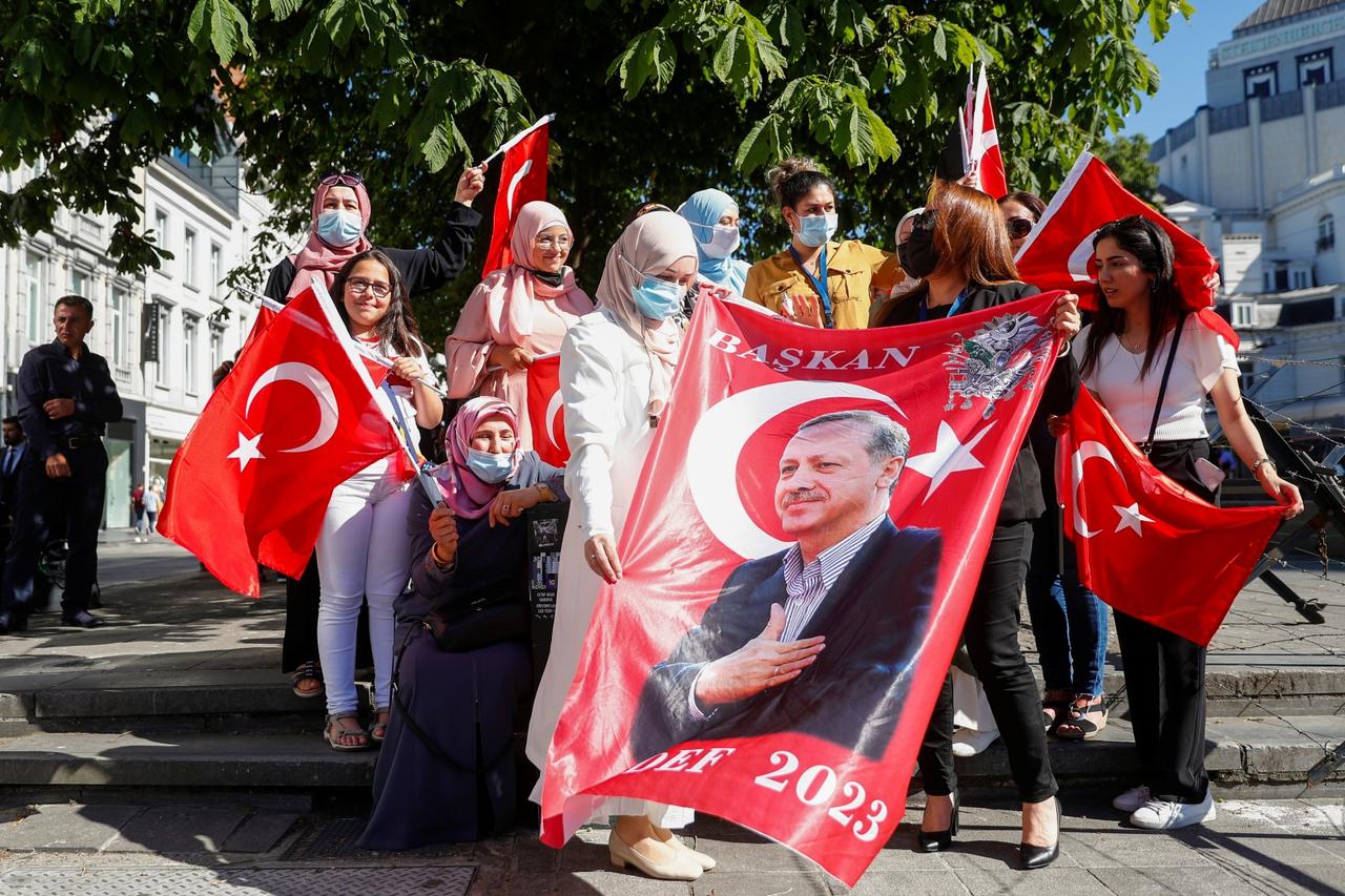Supporters of Turkish President Tayyip Erdogan hold flags and a banner as they gather in front of his hotel in Brussels