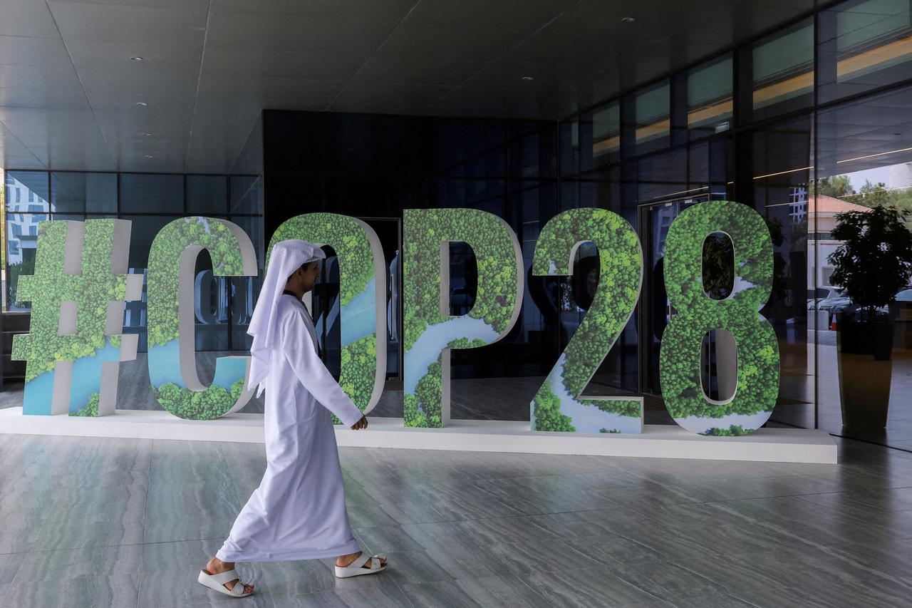 FILE PHOTO: A person walks past a "#COP28" sign in Abu Dhabi