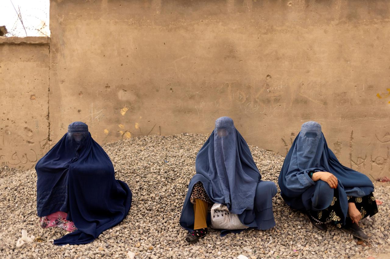 Women wearing burqas pause at the side of a road in Kabul