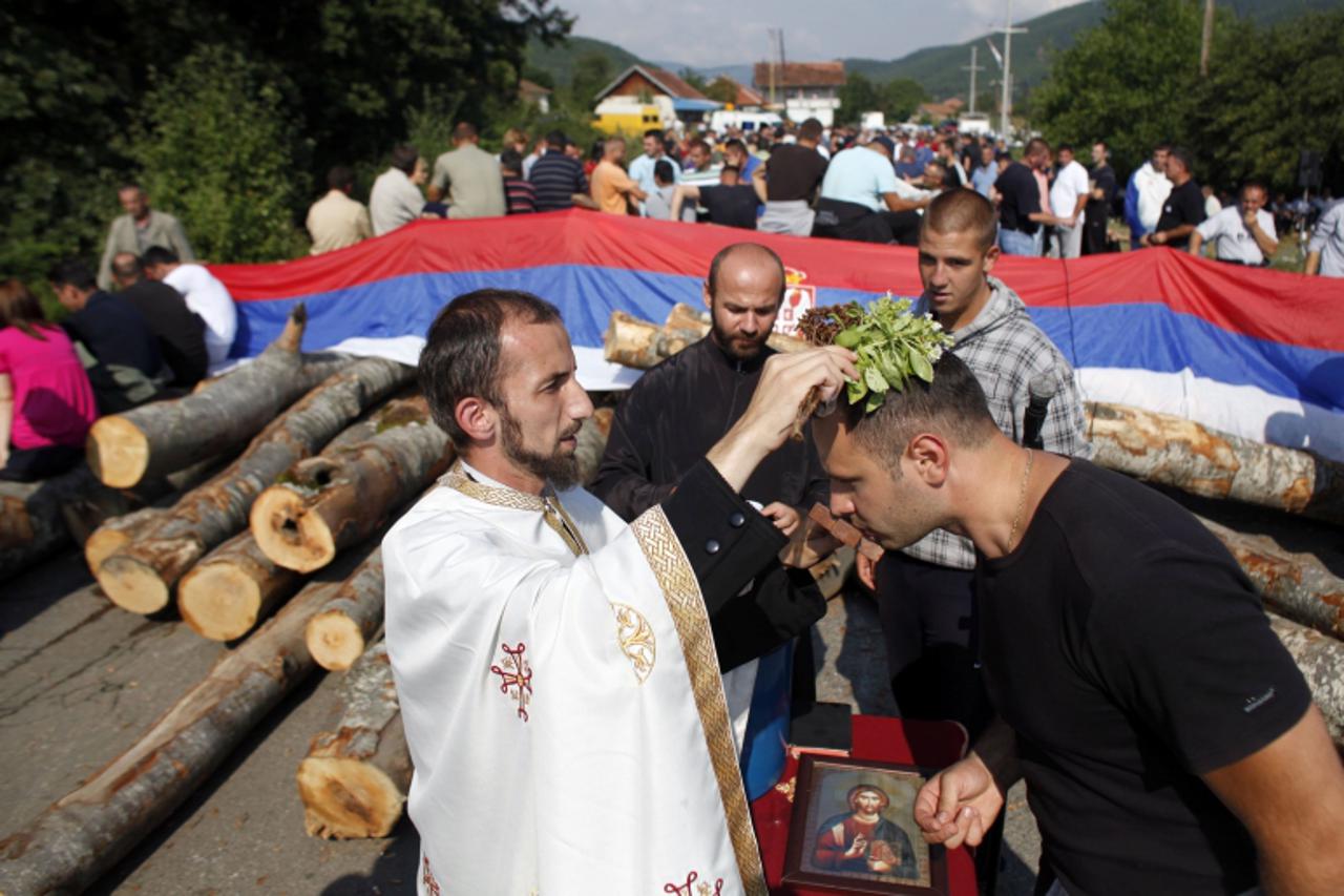 'A Kosovo Serb orthodox priest conducts a religious service near the barricades in the village of Zupce near the town of Zubin Potok August 1, 2011. Serbs vowed to press on with roadblocks and stop NA