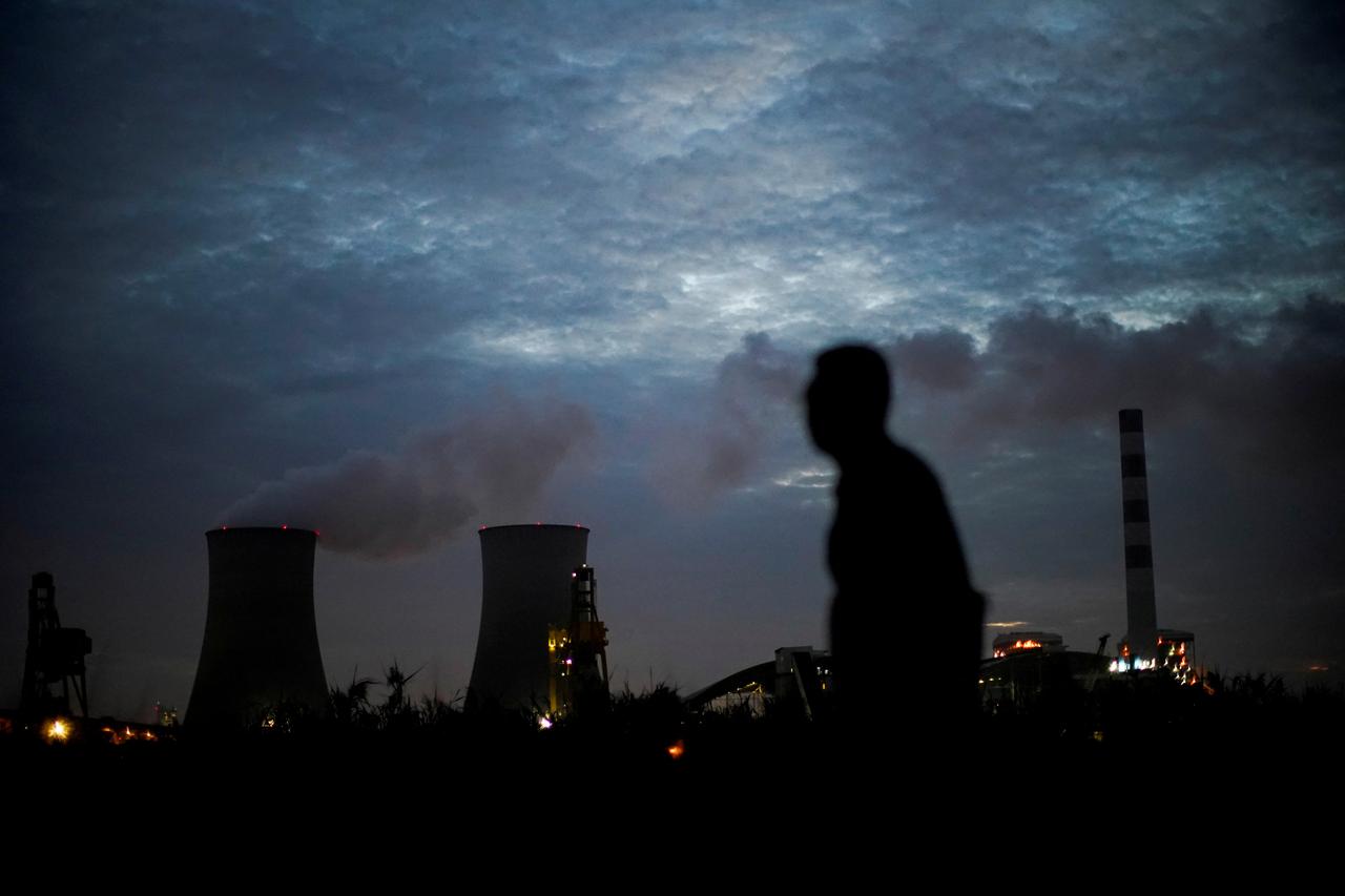 FILE PHOTO: A man walks past a coal-fired power plant in Shanghai