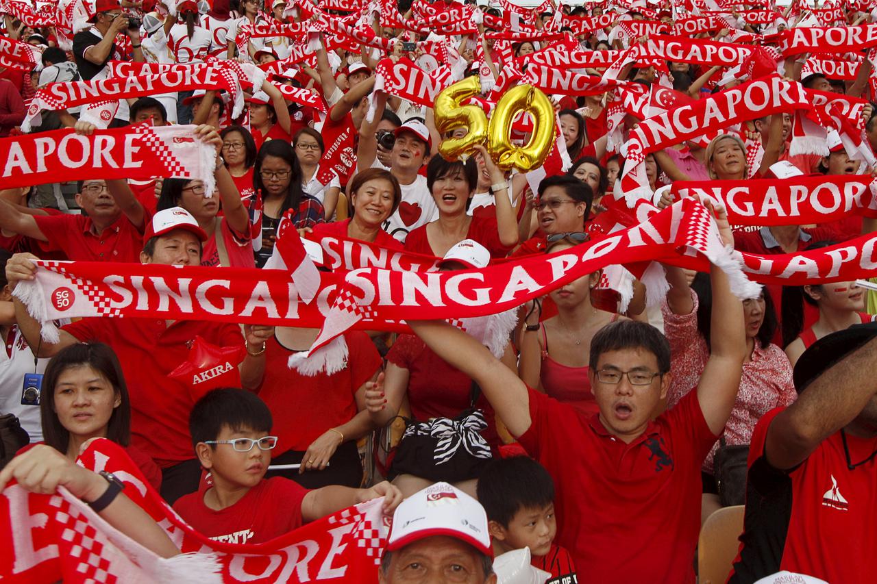 People hold up Singapore banners during Singapore's Golden Jubilee celebration parade at Padang near the central business district August 9, 2015. Singapore marks 50 years of independence on Sunday. An island of 5.5 million people that sits just north of 
