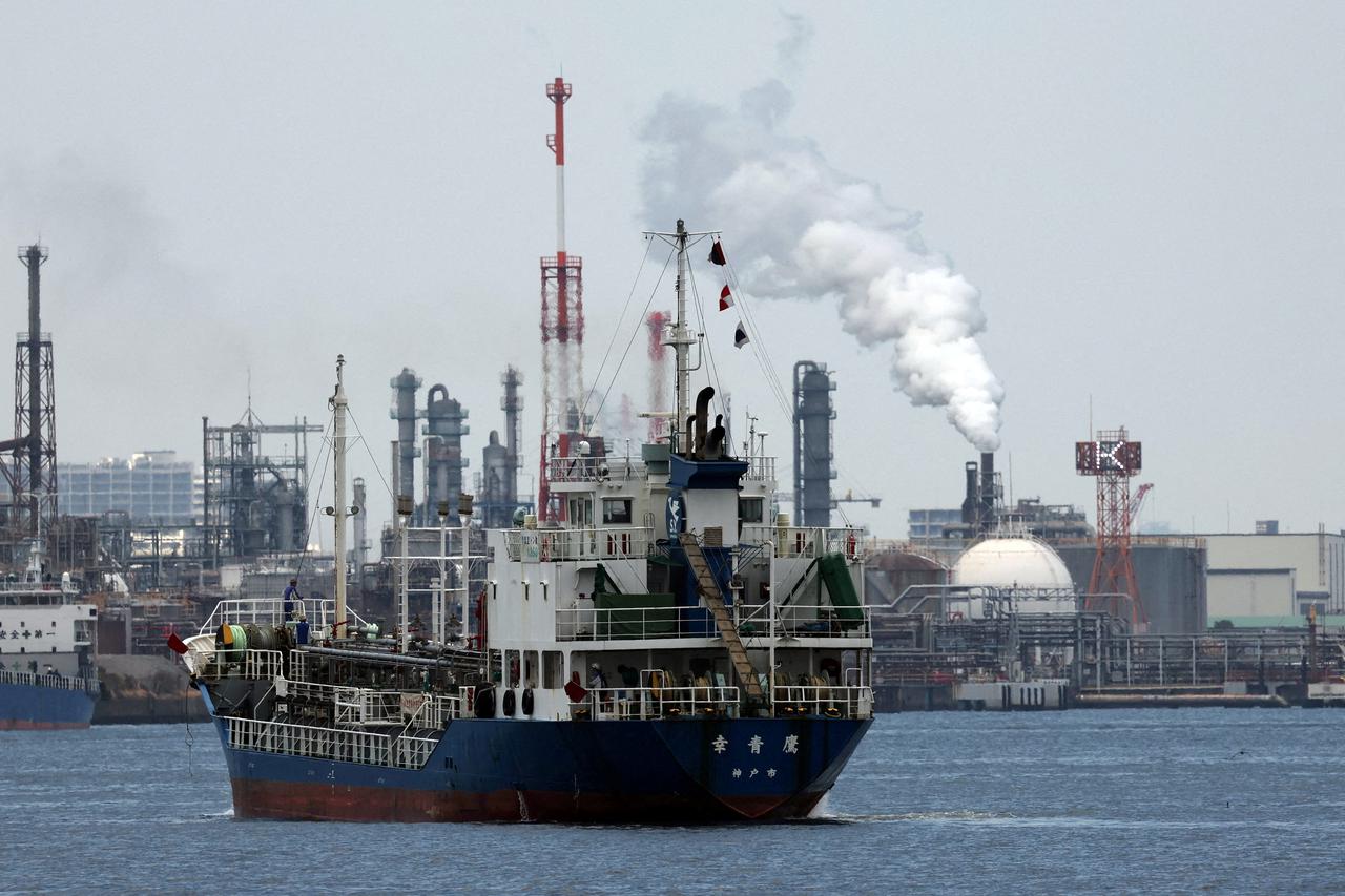 FILE PHOTO: A small tanker sails near an oil refinery in the Keihin Industrial Zone in Kawasaki, south of Tokyo, Japan