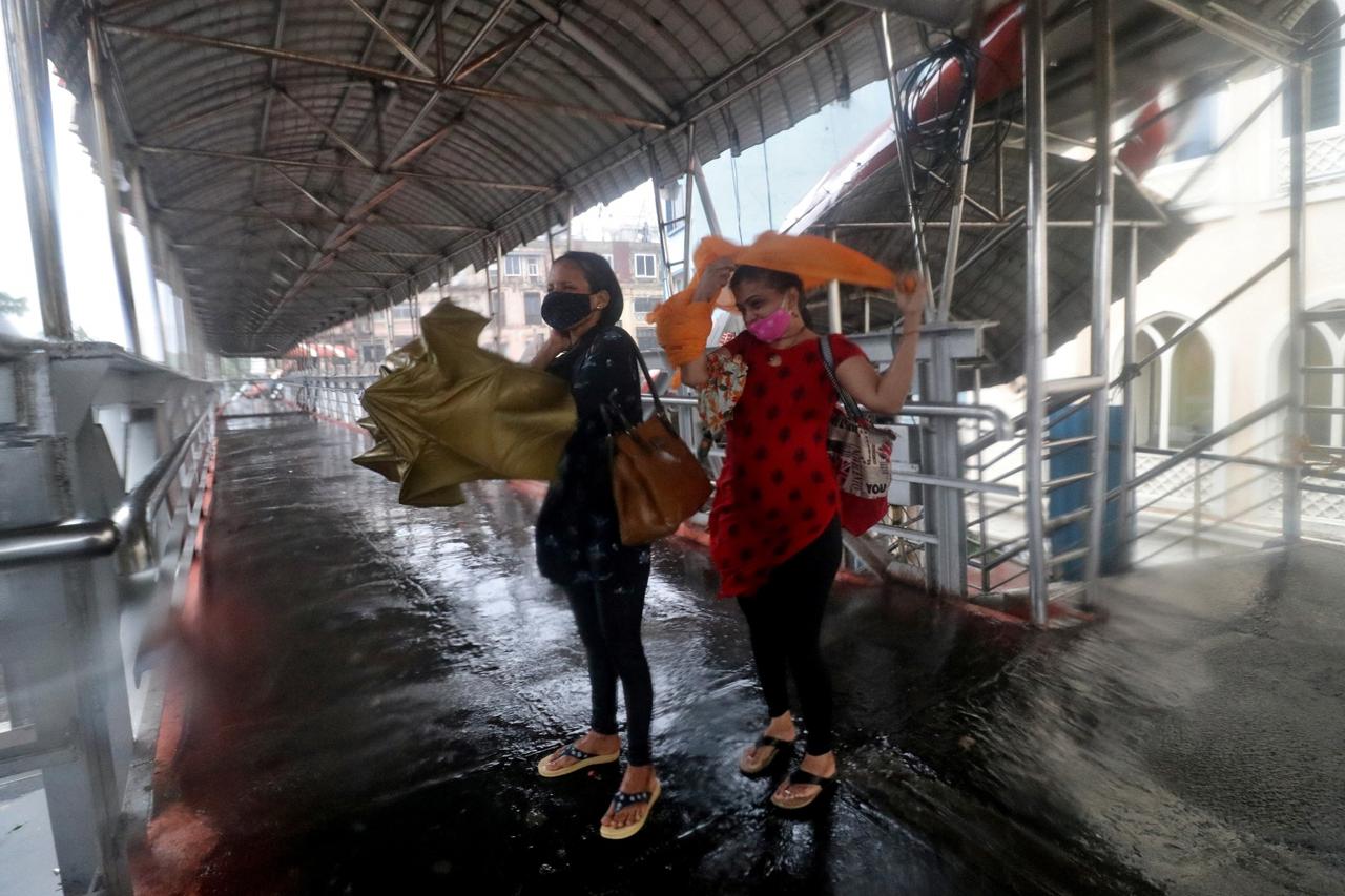 Women take shelter at a pedestrian overpass during heavy rains caused by Cyclone Tauktae in Mumbai