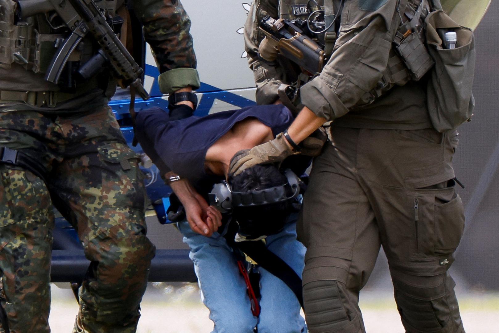 A 26-year-old Syrian man, who is the suspect in custody for a stabbing rampage in the western German city of Solingen in which several individuals were killed, is escorted by police on his way to the Federal Public Prosecutor in Karlsruhe, Germany, August 25, 2024. REUTERS/Heiko Becker Photo: Heiko Becker/REUTERS