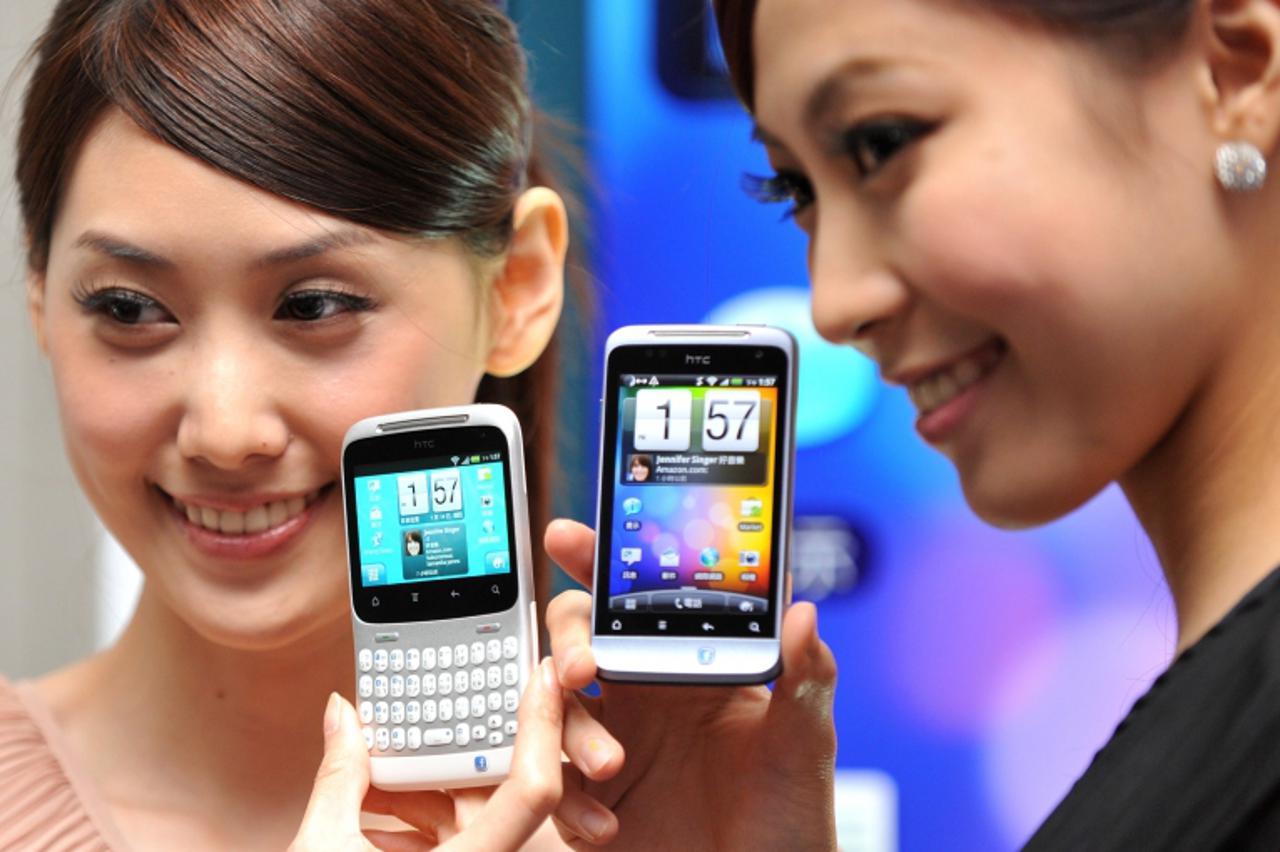\'A woman displays an HTC \'ChaCha\' (L) mobile phone during a press conference in Taipei on July 14, 2011. The model is expected to hit the local market late July with a price tag of 342 USD. AFP PHO