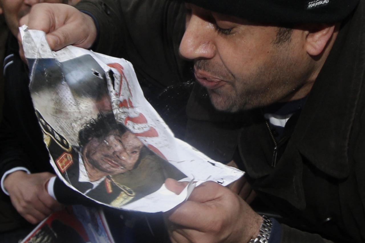 \'A demonstrator spits at a picture of Libya\'s Muammar Gaddafi  during protests outside the Libyan Embassy in London February 20, 2011. Libyans protesting against Muammar Gaddafi\'s rule appeared to 