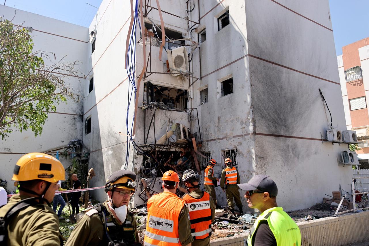 Israeli soldiers work at a damaged building following a rocket attack from Gaza, in Ashdod