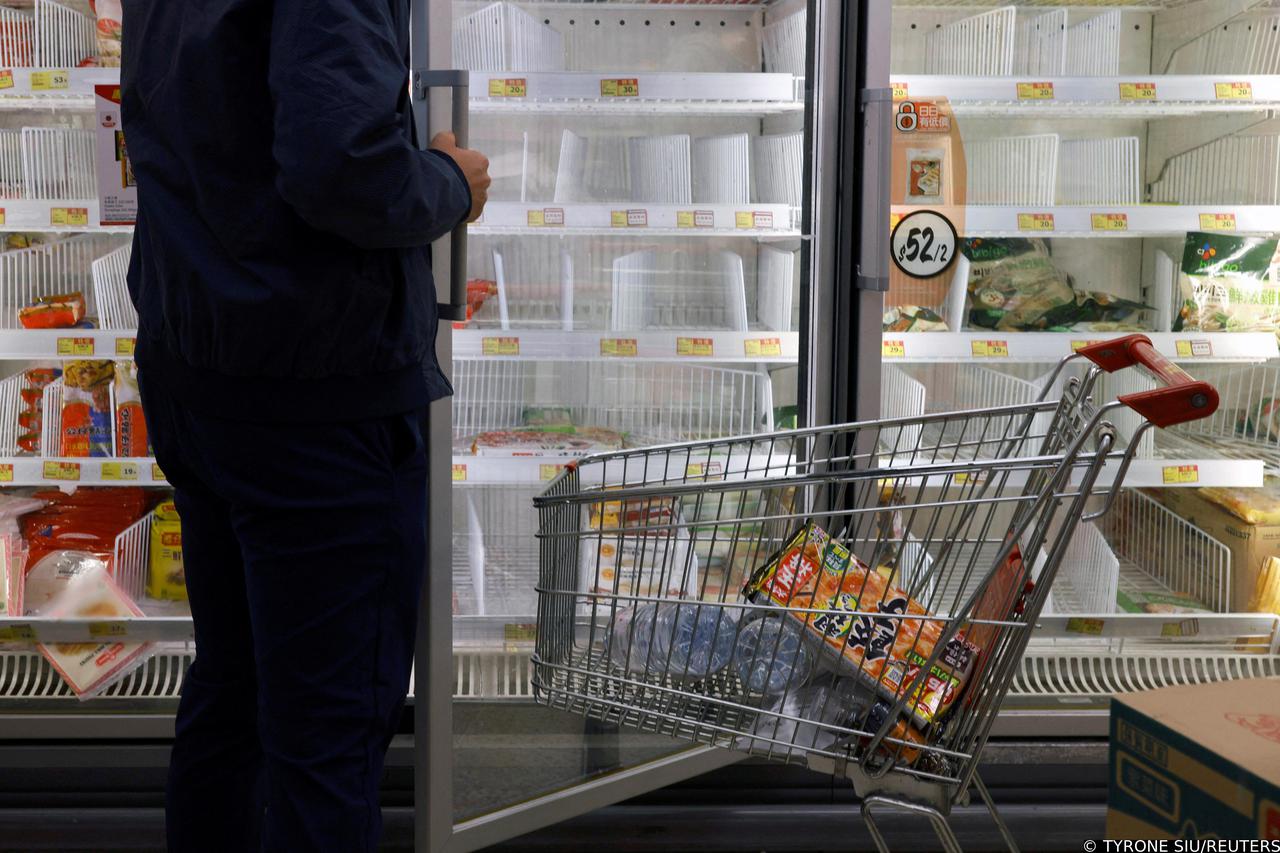 A customer wearing a mask shops in front of partially empty shelves at a supermarket in Hong Kong