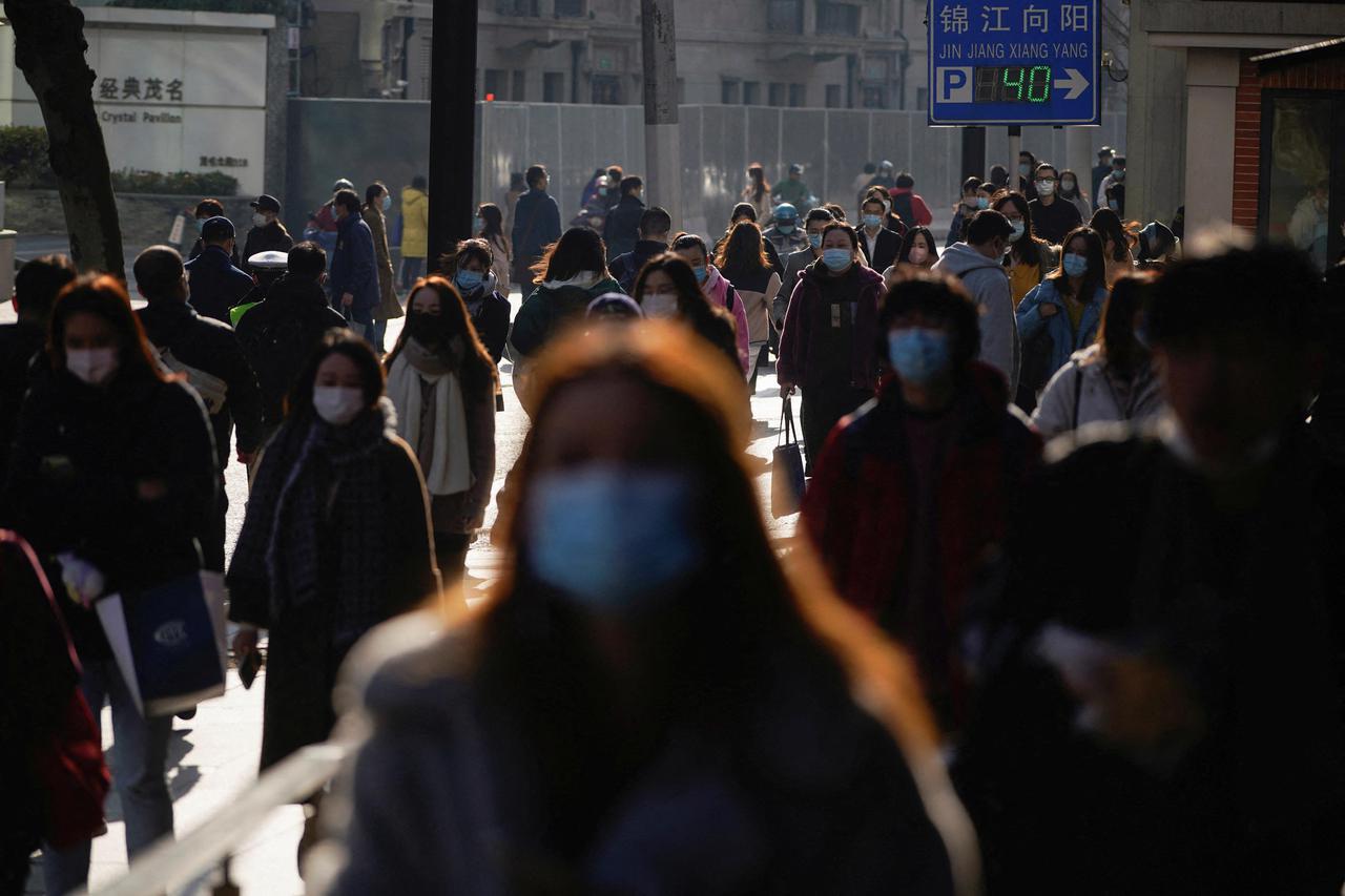 FILE PHOTO: People wearing protective masks walk on a street, following new cases of the coronavirus disease (COVID-19), in Shanghai