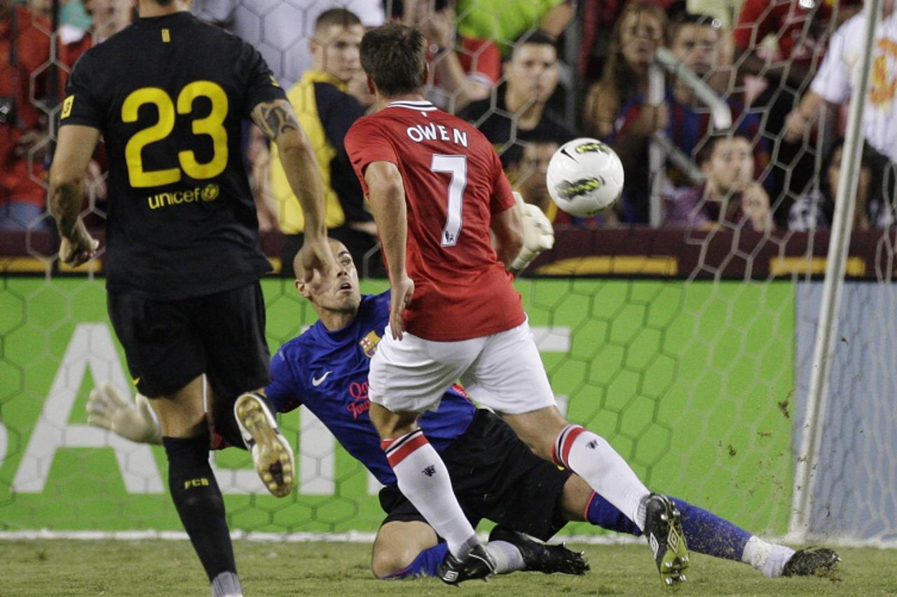 'Manchester United\'s Michael Owen (R) scores past Barcelona\'s goalkeeper Victor Valdes (C) during the second half of their 2011 Herbalife World Football Challenge soccer match in Landover, Maryland,