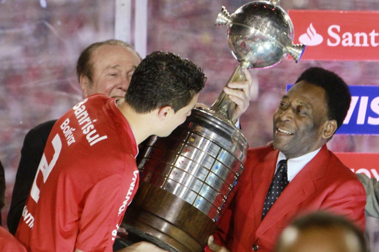 'Bolivar (front L) of Brazil\'s Internacional receives the trophy from Pele (R) and CONMEBOL president Nicolas Leoz (back L) after defeating Mexico\'s Guadalajara Chivas in the second-leg final soccer