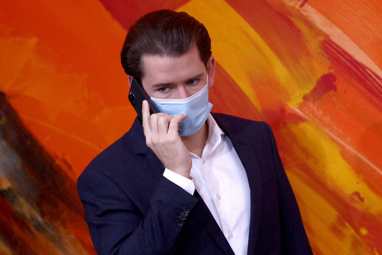 Austria's Chancellor Sebastian Kurz wearing a protective face mask uses a smartphone as he arrives for the budget speech at the parliament  in Vienna