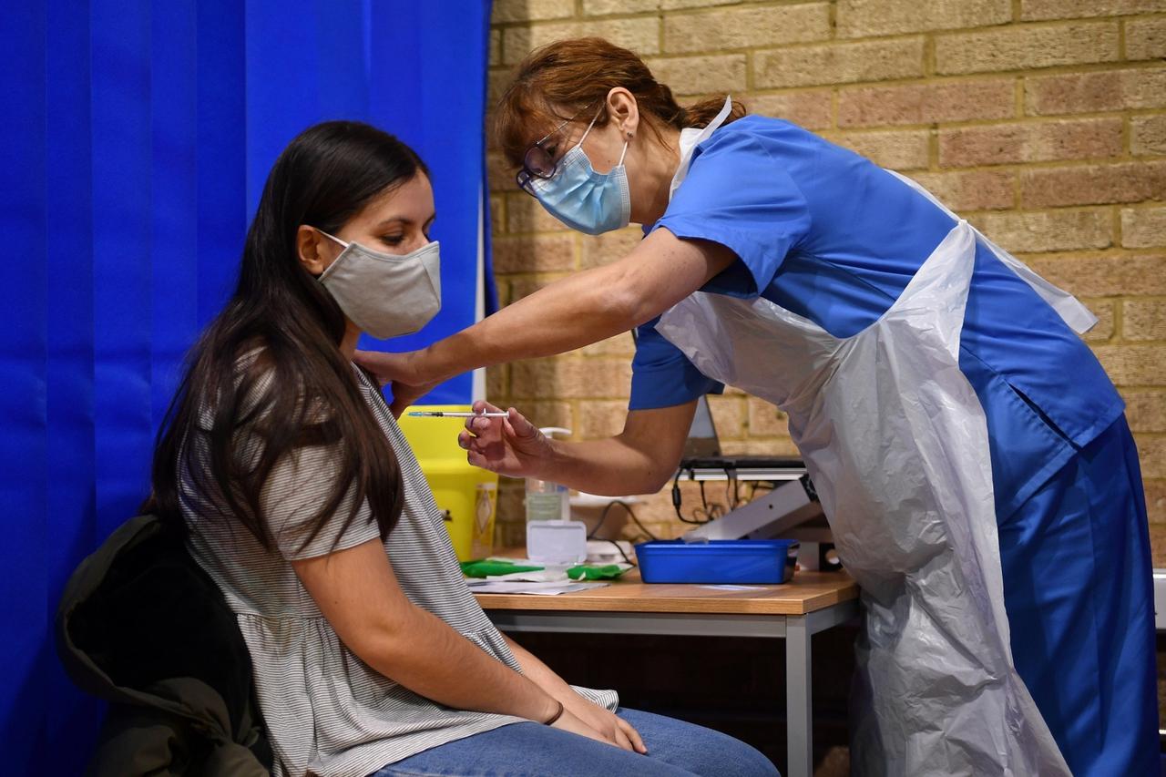 A nurse administers the Pfizer/BioNTech COVID-19 vaccine to a woman at a vaccination centre in Cardiff
