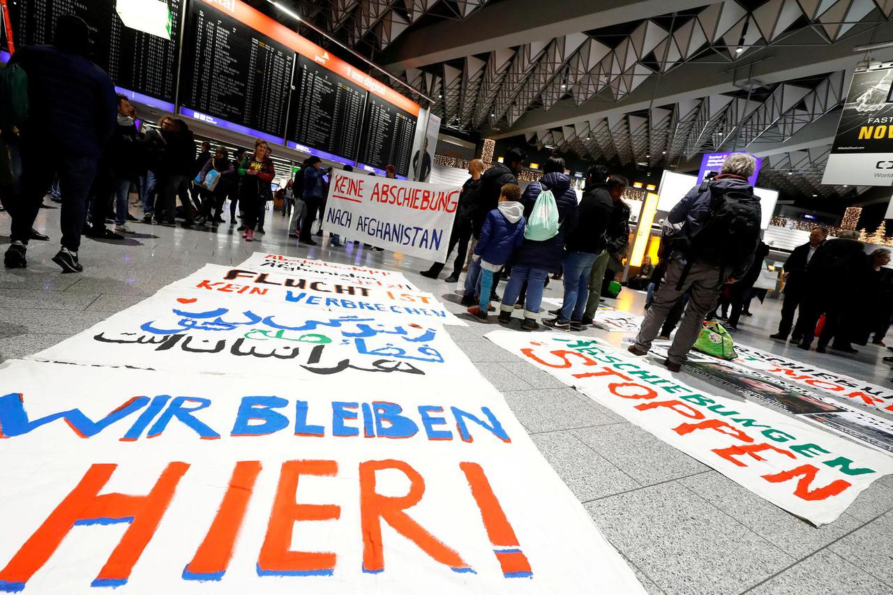FILE PHOTO: Protestors display placards reading "We stay here", "No deportation to Afghanistan" and "Fleeing is not a crime" as they demonstrate against the deportation of people to Afghanistan at Fraport airport in Frankfurt