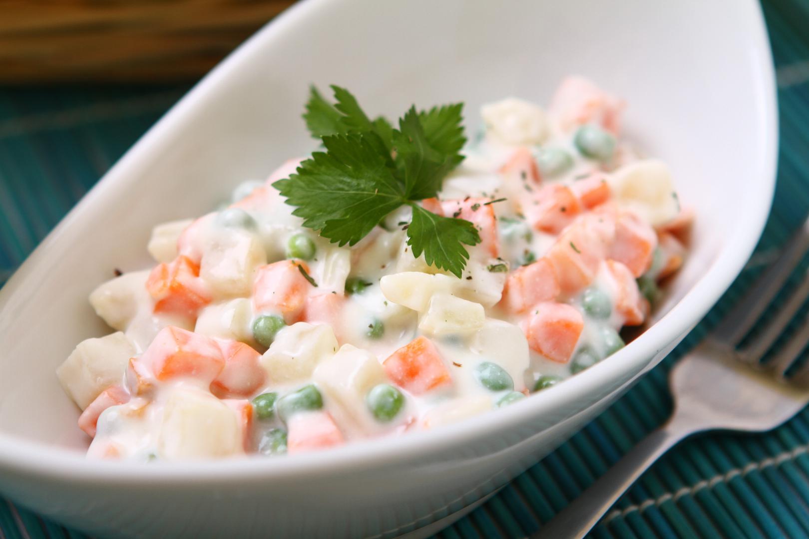 Priprema: Krumpir i mrkvu operite, ogulite i narežite na sitne kockice. Grašak ostavite cijeli. Sve skuhajte u blago posoljenoj vodi dok ne omekša, ali pazite da se ne raskuha. Ocijedite i pustite da se potpuno ohladi. Nasjeckajte kisele krastavce i naribajte jabuku. Jabuku možete lagano nakapati limunovim sokom da ne potamni. U velikoj zdjeli pomiješajte kuhano povrće, krastavce i jabuku. Dodajte majonezu, kiselo vrhnje i senf, te začinite solju i paprom. Po želji dodajte još limunovog soka ako volite svježiji okus. Dobro promiješajte i ostavite u hladnjaku barem dva sata da se okusi povežu.