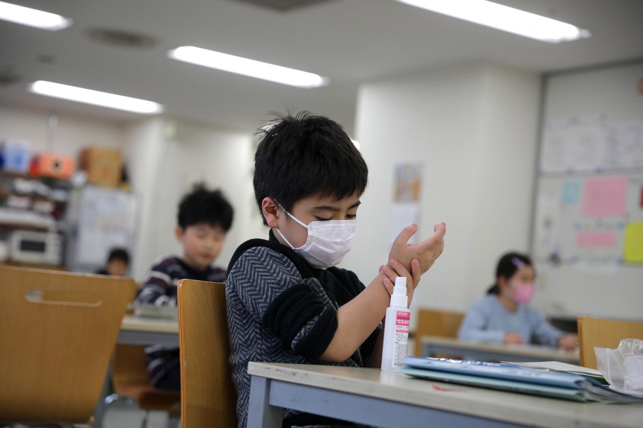 Child, wearing a protective face mask, following an outbreak of coronavirus, uses hand sanitizer at "Stella Kids", daycare center in Tokyo