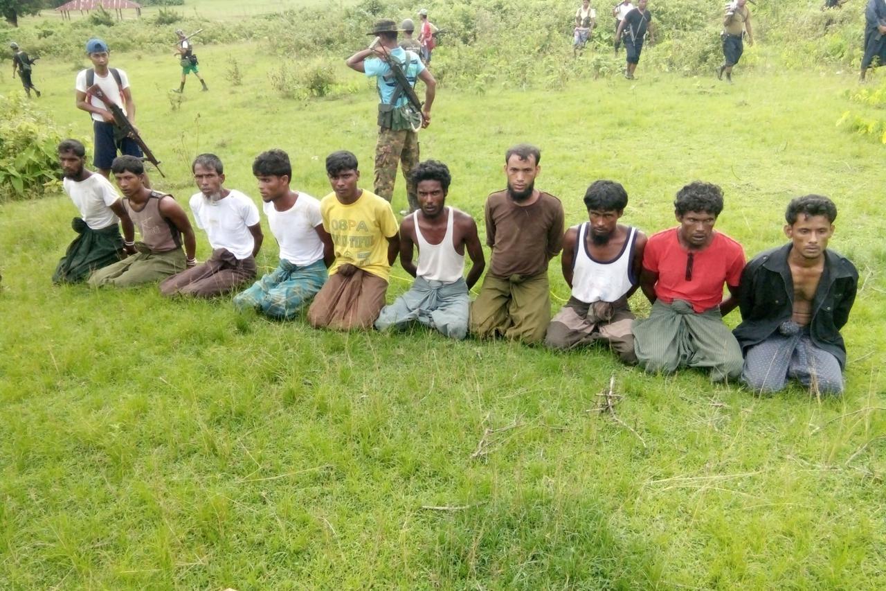 FILE PHOTO: Ten Rohingya men with their hands bound kneel as members of the Myanmar security forces stand guard in Inn Din village