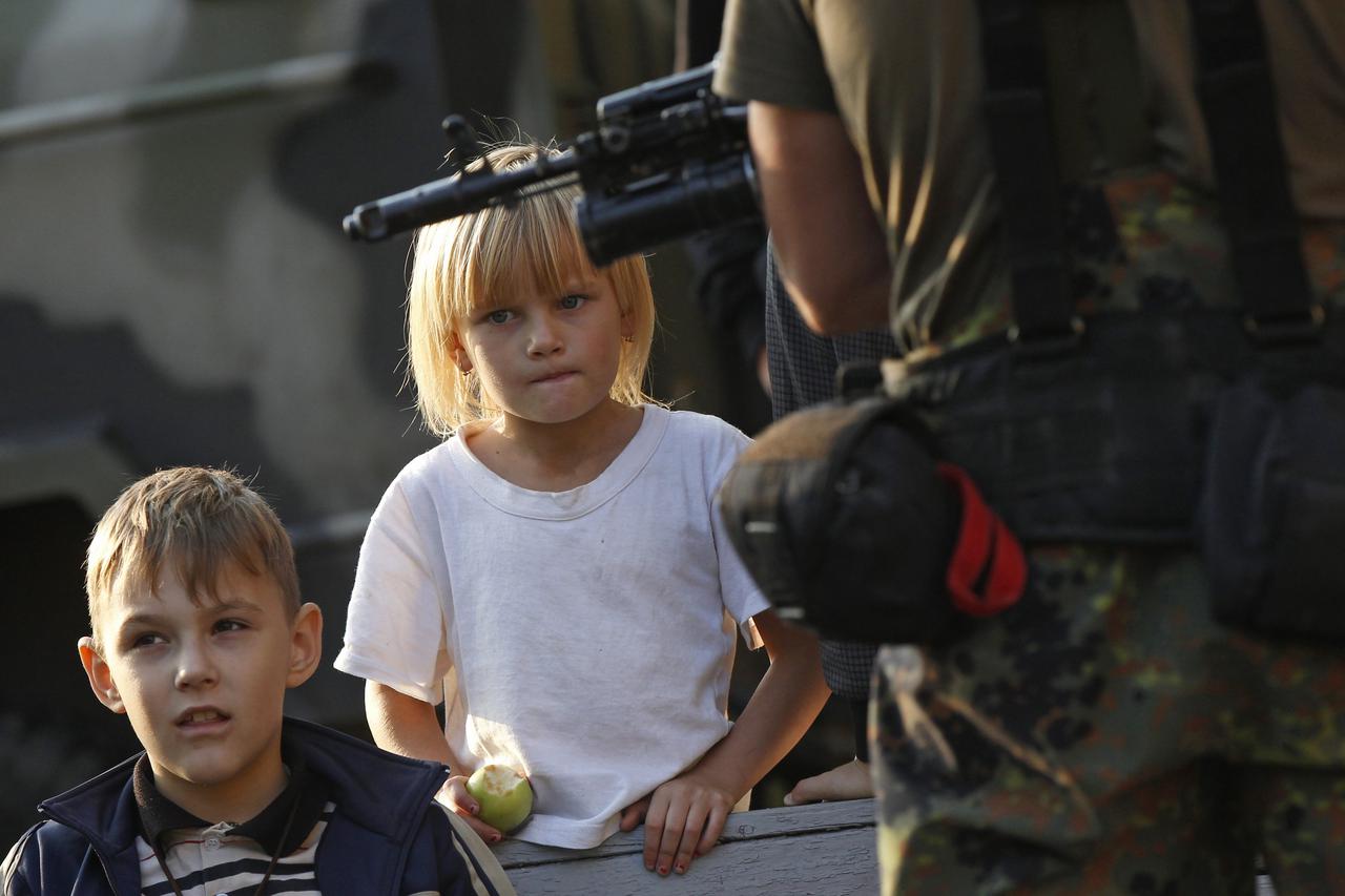 Children watch a negotiation take place between Ukrainian and Russian officers at a temporary military base in Soledar, eastern Ukraine September 27, 2014. Talks began on Friday to mark out a 30-km (19-mile) buffer zone between Ukrainian government forces