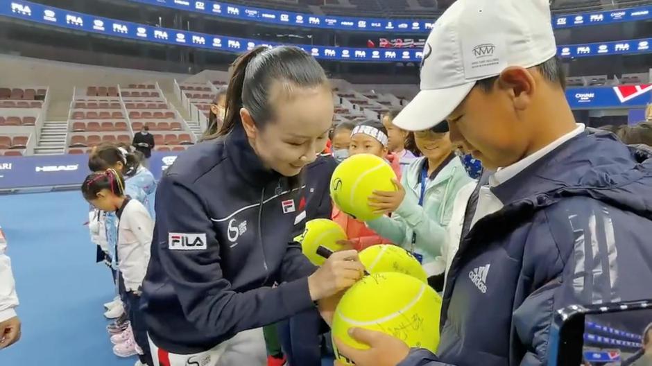 Chinese tennis player Peng Shuai signs large-sized tennis balls at the opening ceremony of Fila Kids Junior Tennis Challenger Final in Beijing