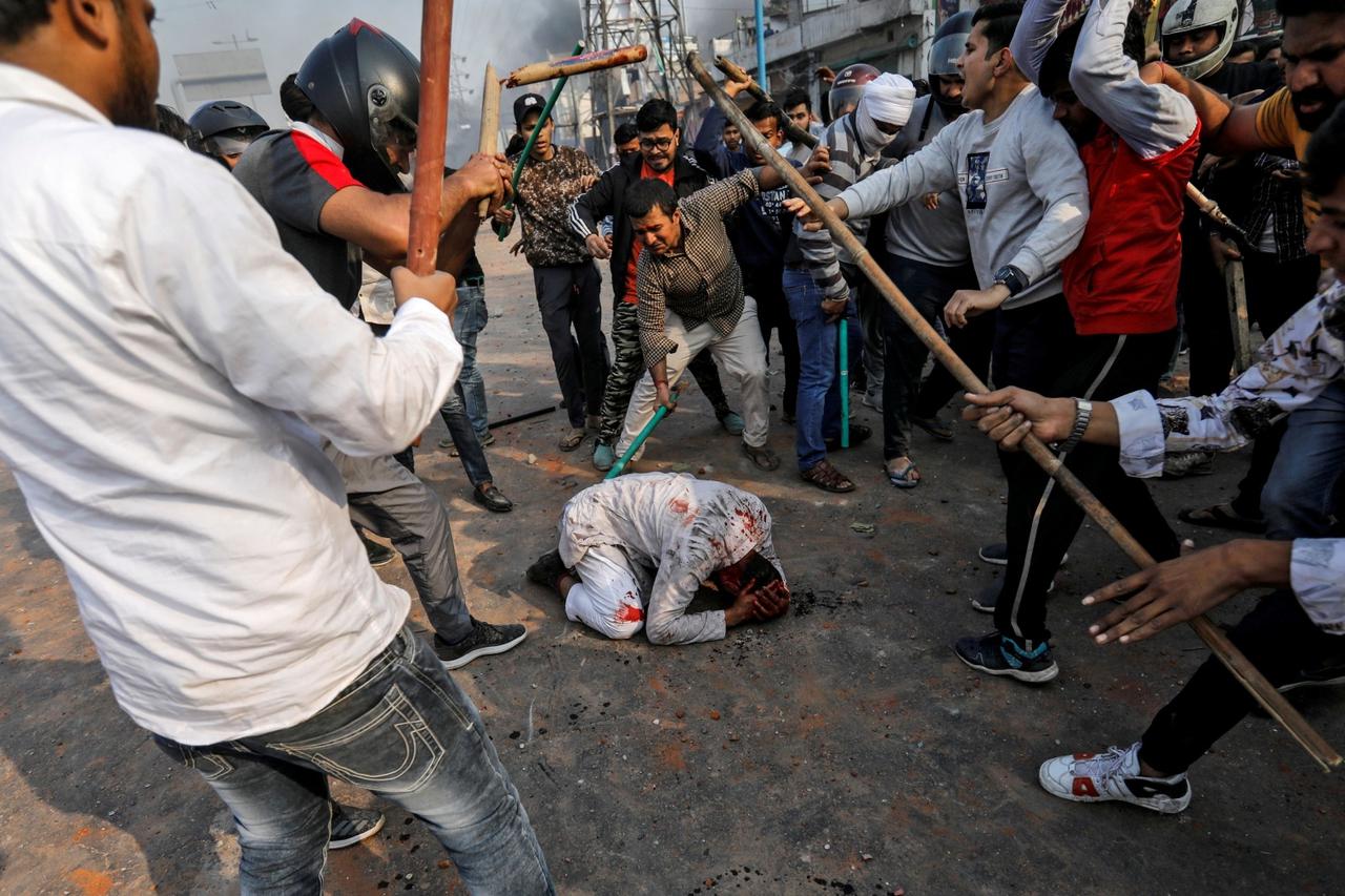 Skupina hinduista palicama udara muslimana koji nemoćno kleči na podu