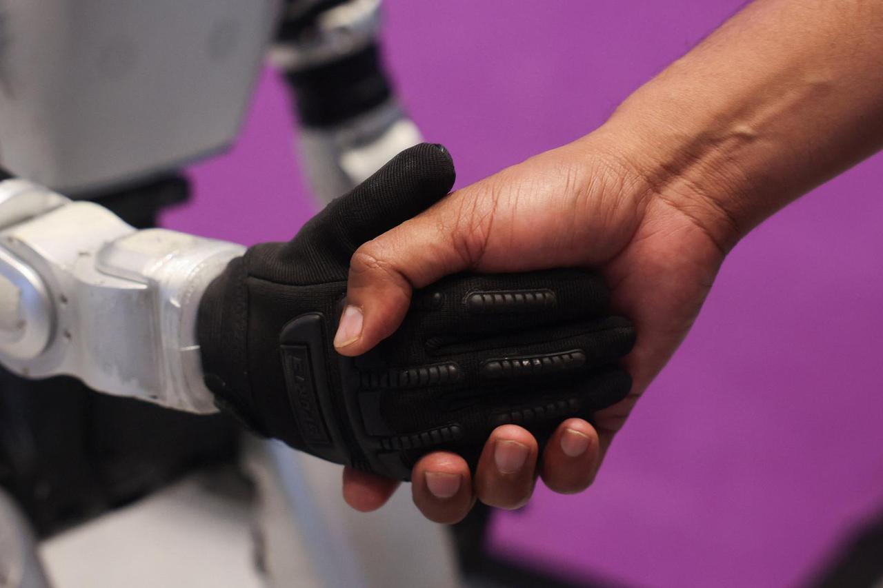 A man shakes the hand of a Chinese G1 humanoid robot made by Unitree Robotics at the ImagiNxt conference in Mumbai