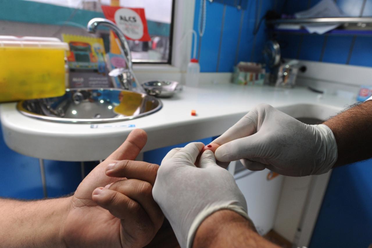 'A medical personel checks the finger of a volunteer, who takes part in a AIDS and HIV Testing organized by the community of volunteers, friends and supporters of the ALCS (Moroccan association agains