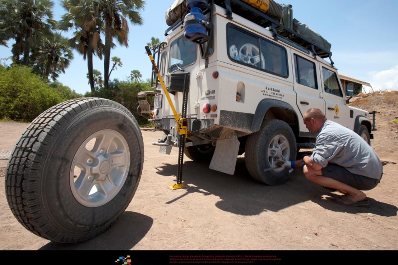'A flat tire of a Land Rover Defender is changed in Palmwag, Namibia, 26 November 2010. Photo: Tom Schulze'