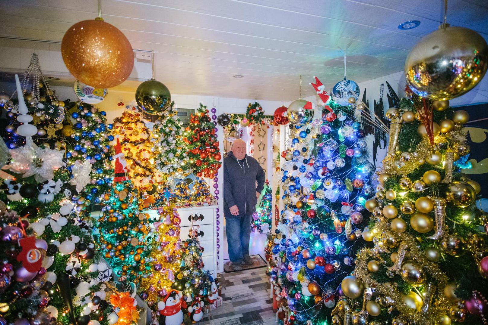 06 December 2021, Lower Saxony, Rinteln: Thomas Jeromin stands among Christmas trees in his house. Thomas Jeromin has set a new world record with 444 Christmas trees in his house. The record institute for Germany was there on Monday to check and confirmed the record. Photo: Ole Spata/dpa