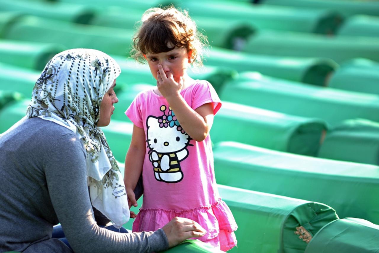 \'A Bosnian Muslim woman comforts a child among the 613 coffins laid out in preparation for mass burrial ceremony at the Srebrenica Memorial Cemetary in Potocari on July 10, 2011. Tens of thousands of