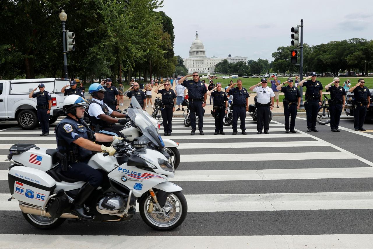 Law enforcement officers salute as a ceremonial procession in honor of a police officer wounded at the Pentagon passes the U.S. Capitol in Washington