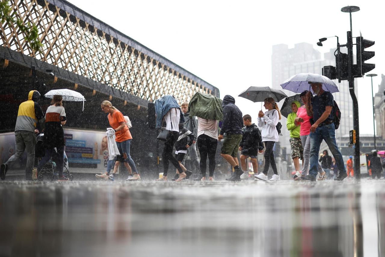 People walk through heavy rainfall, amid the coronavirus disease (COVID-19) outbreak, in London