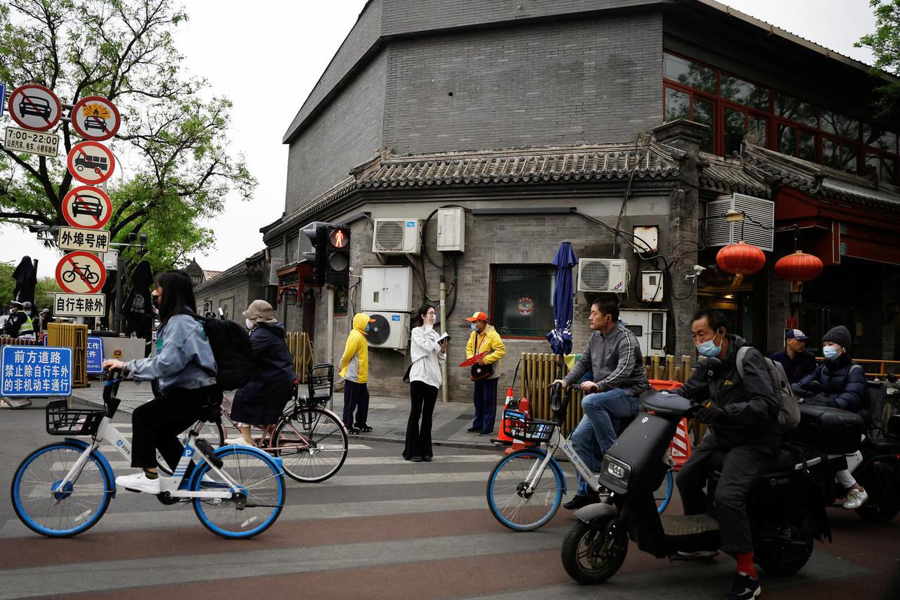 People ride bicycles and scooters on a street during morning rush hour, in Beijing